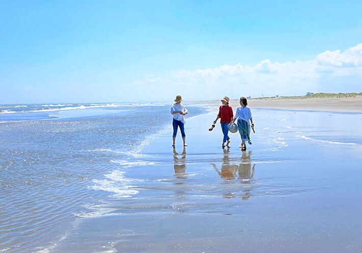 九十九里浜を裸足で歩く女性3人